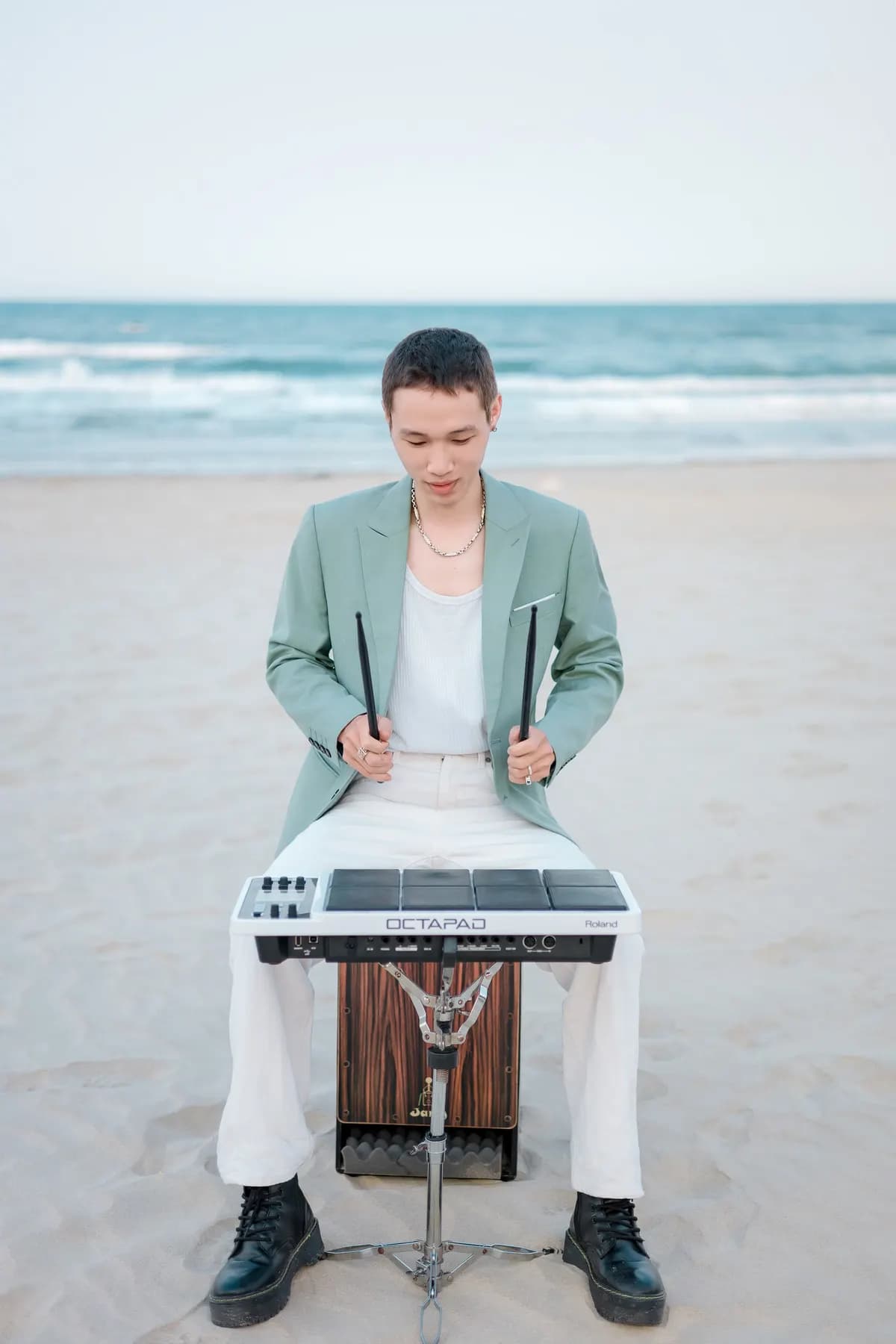 Percussionist seated at a drum pad on the sand