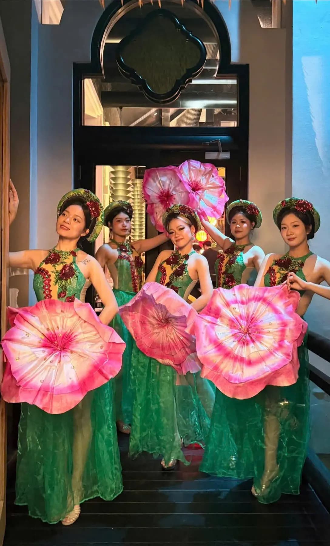 Dancers in green holding pink lotus fans