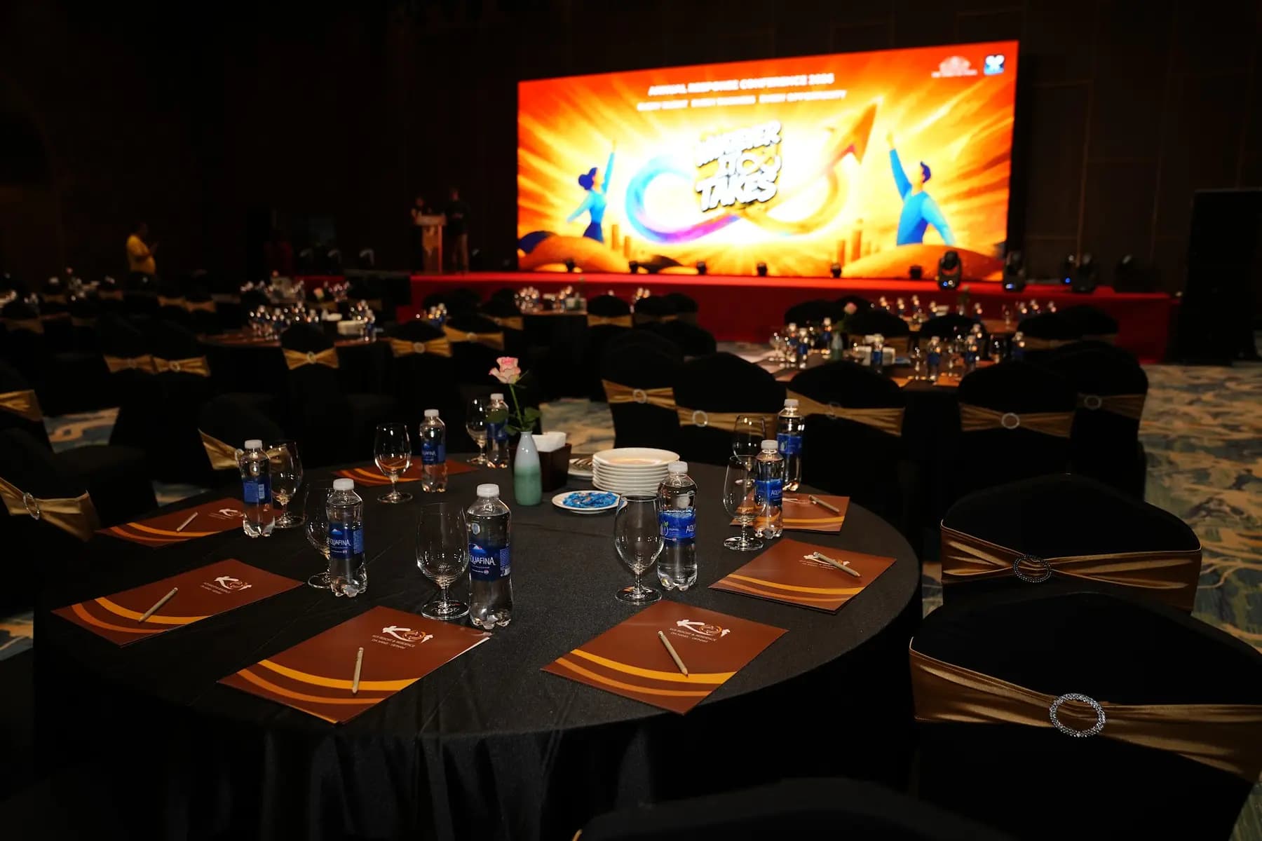 Ballroom set with round tables facing a stage and LED backdrop