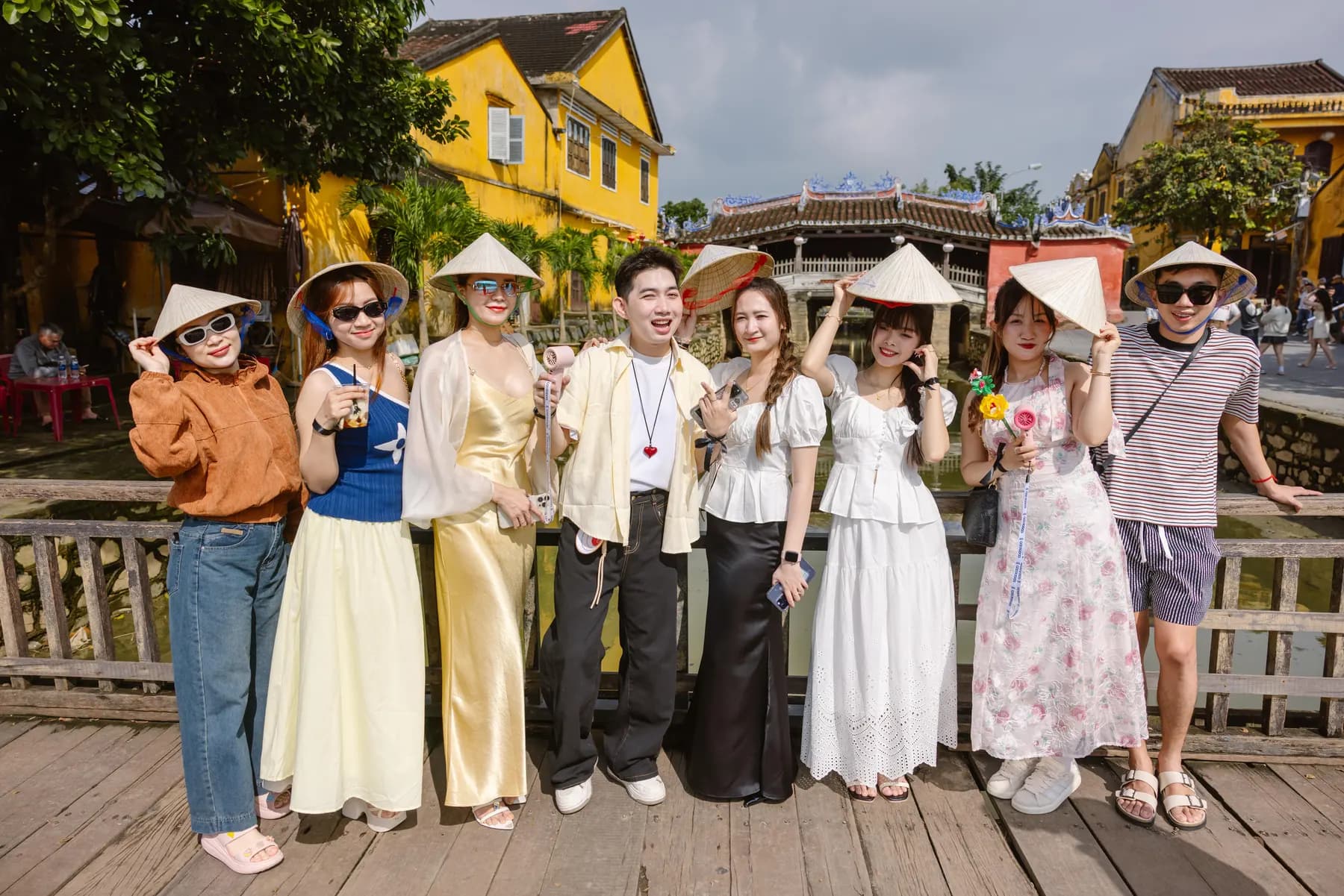 Guests in conical hats posing by the Japanese Covered Bridge in Hoi An