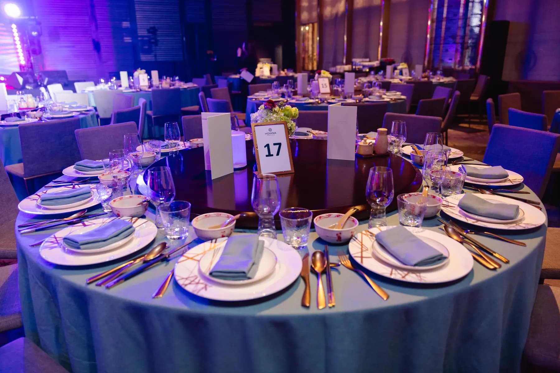 Round gala table in pale blue with numbered table card and glassware