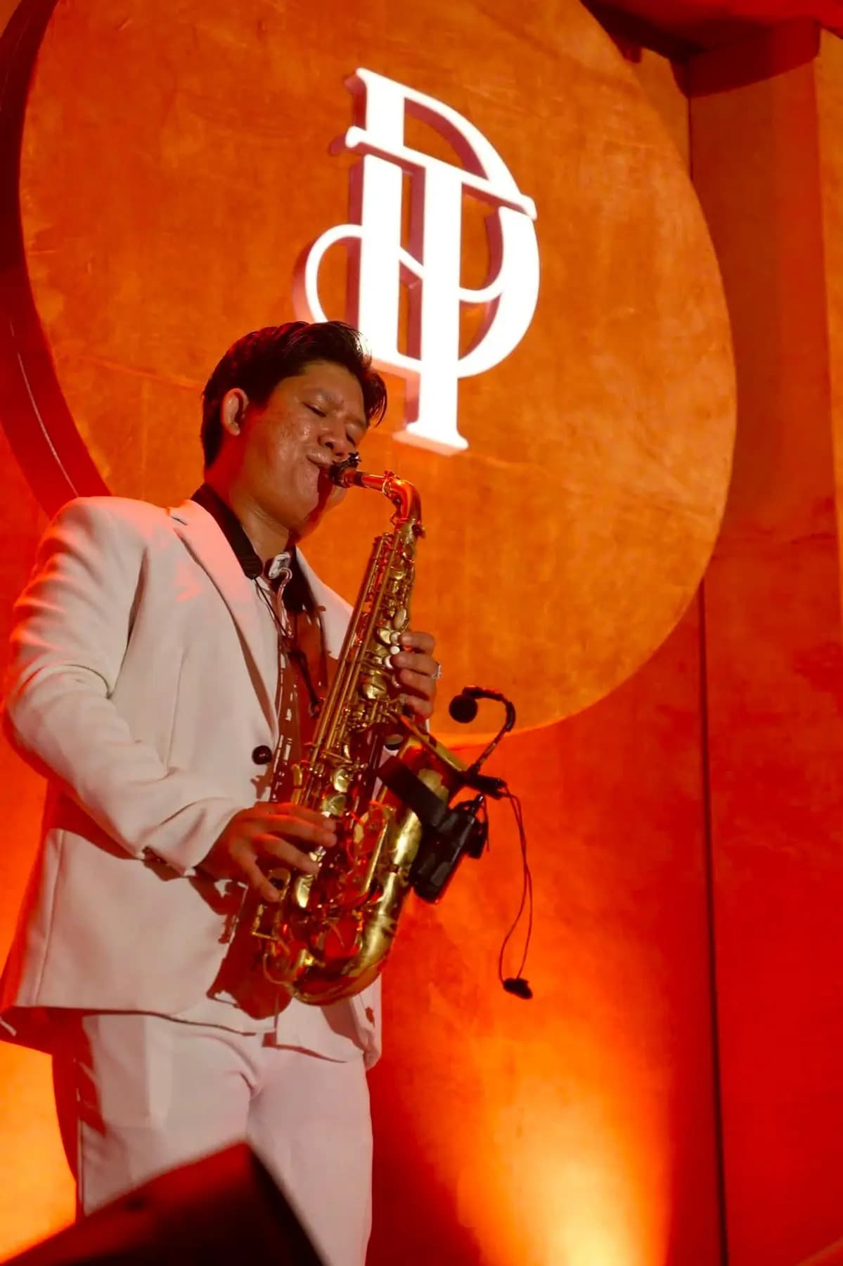 Saxophonist performing under warm red stage light