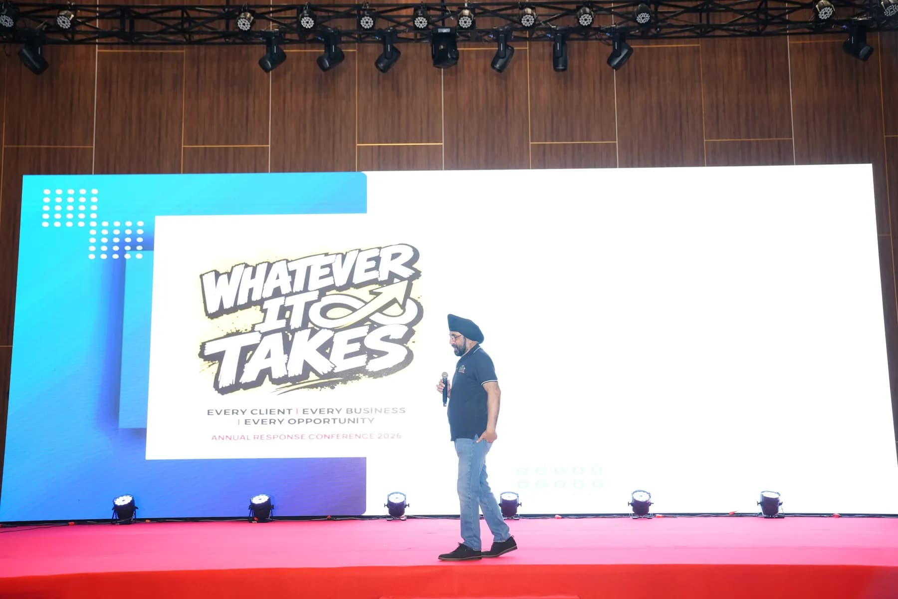 Presenter on stage with slides on the LED wall