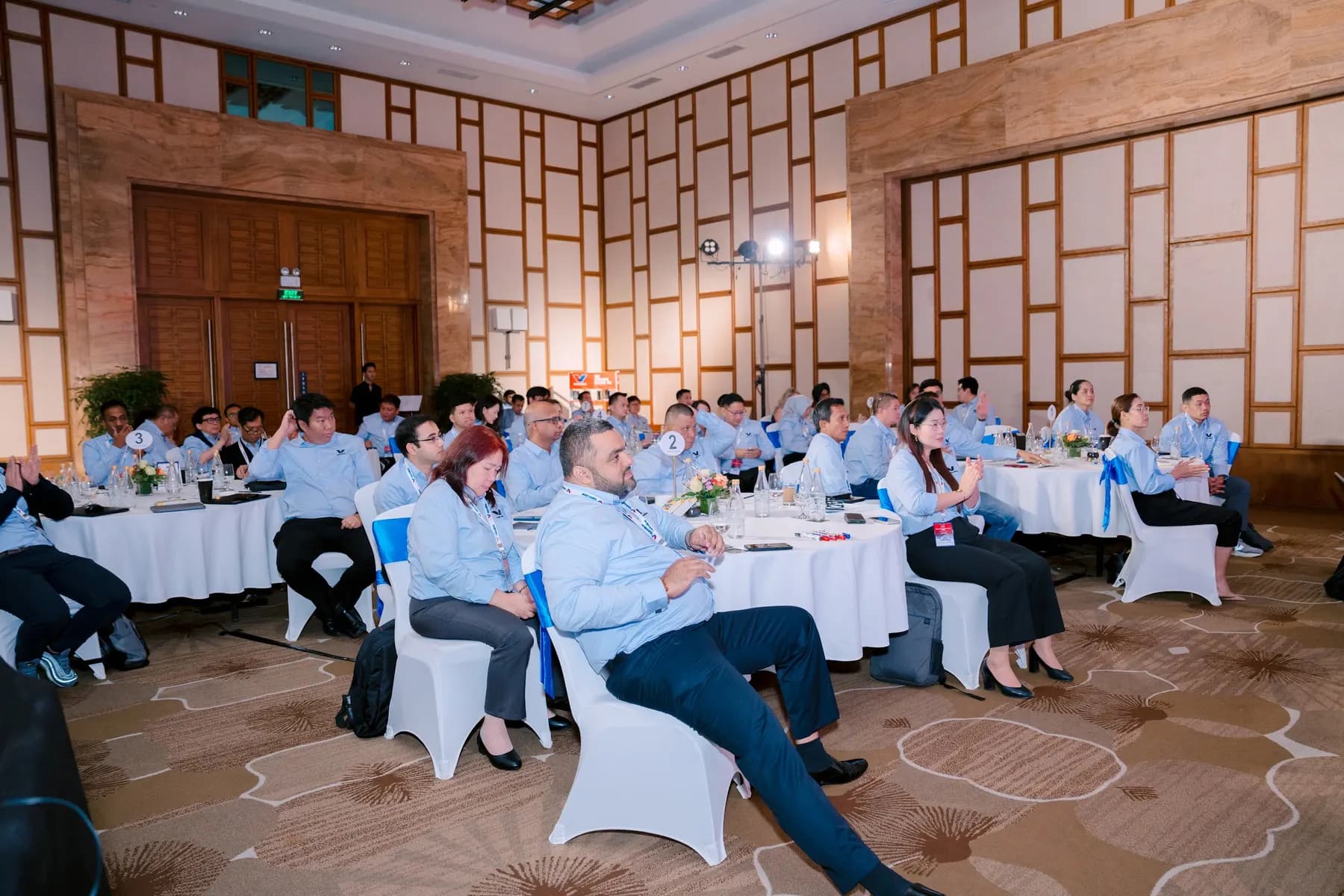 Conference delegates seated at round tables in the ballroom