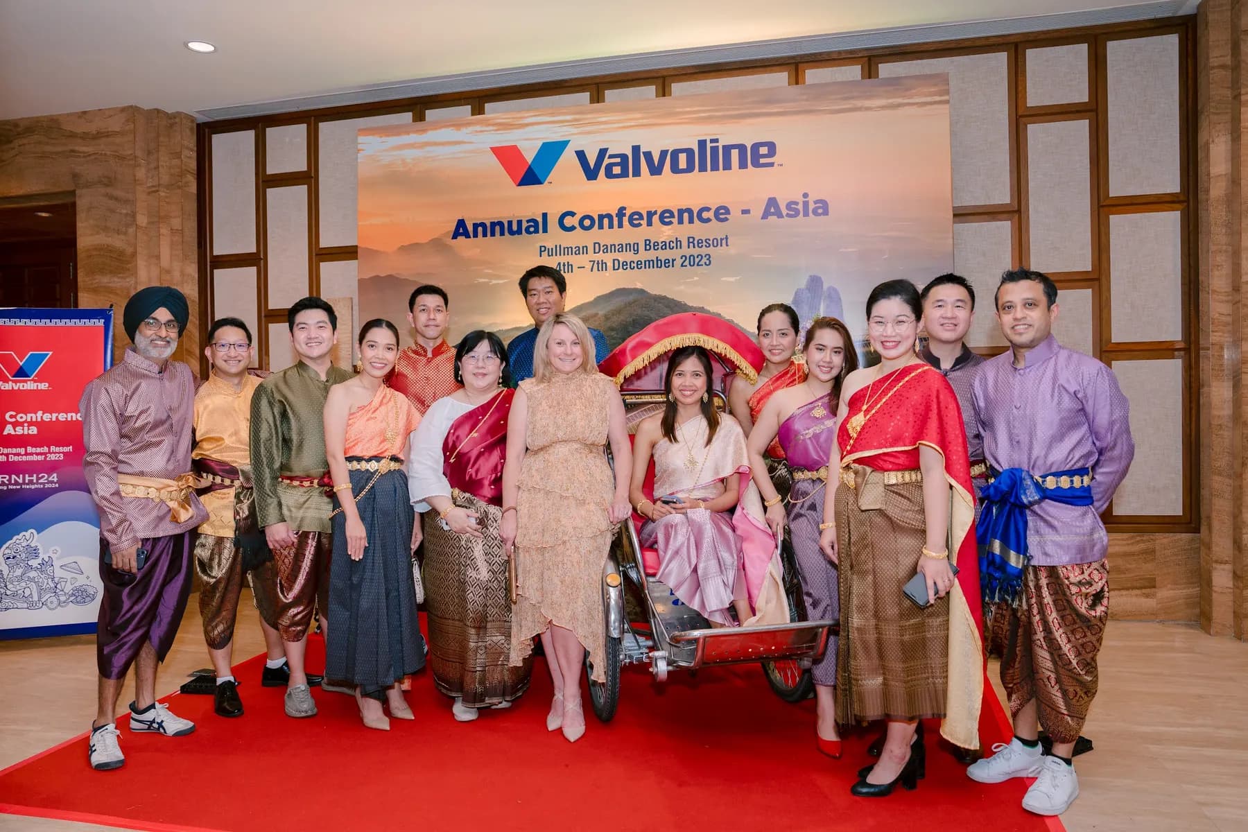 Guests in traditional dress posing with a cyclo at the photo backdrop