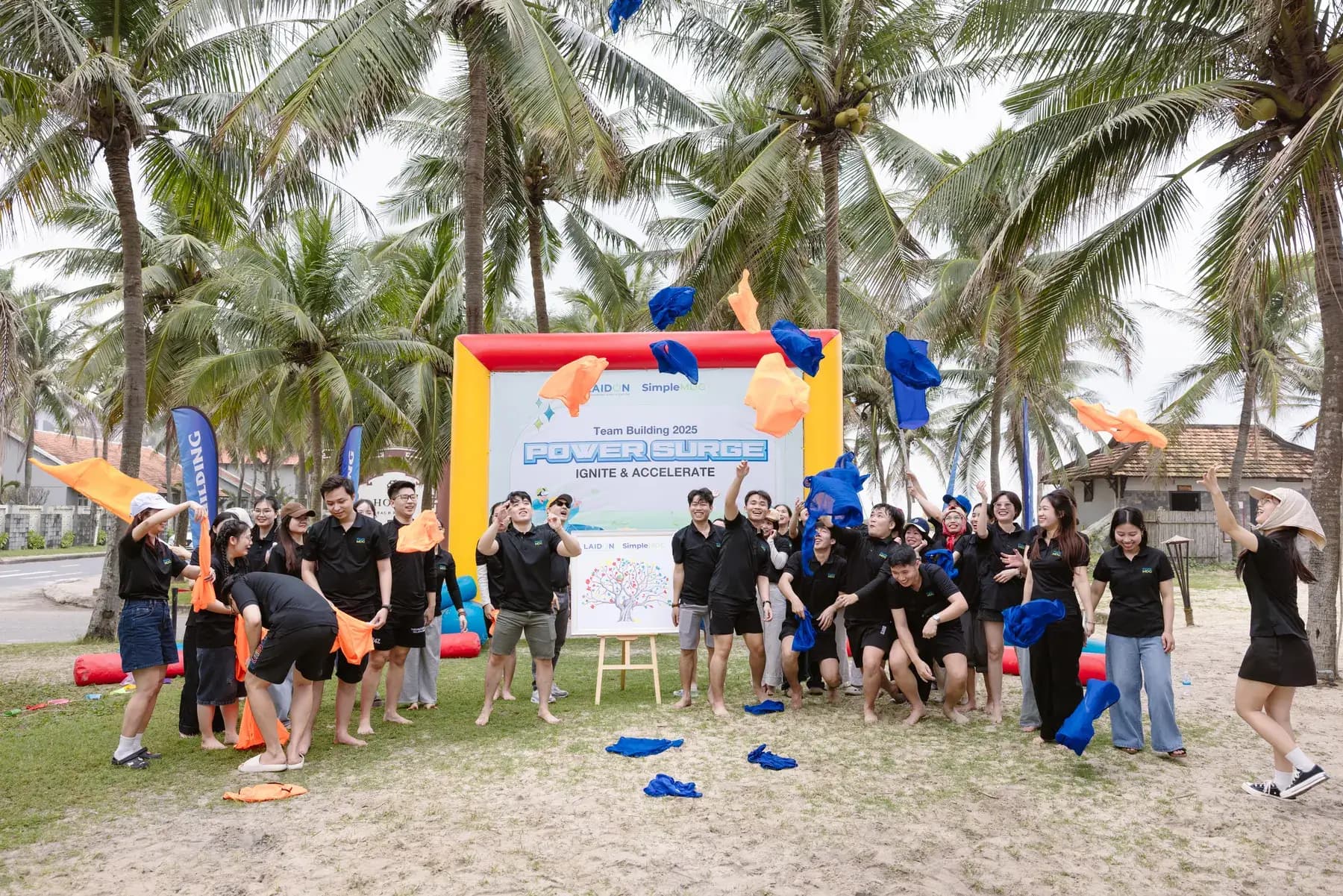 Final group photo with bibs thrown in the air in front of the backdrop