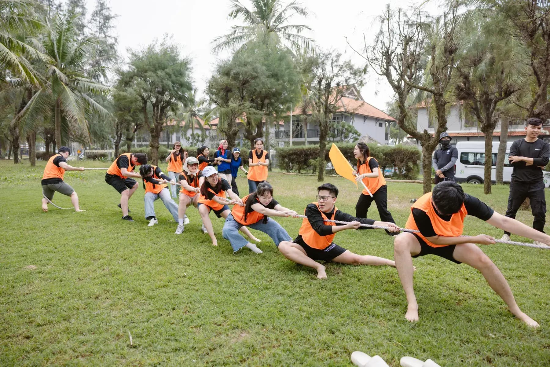 Orange team leaning back in a tug of war on the grass