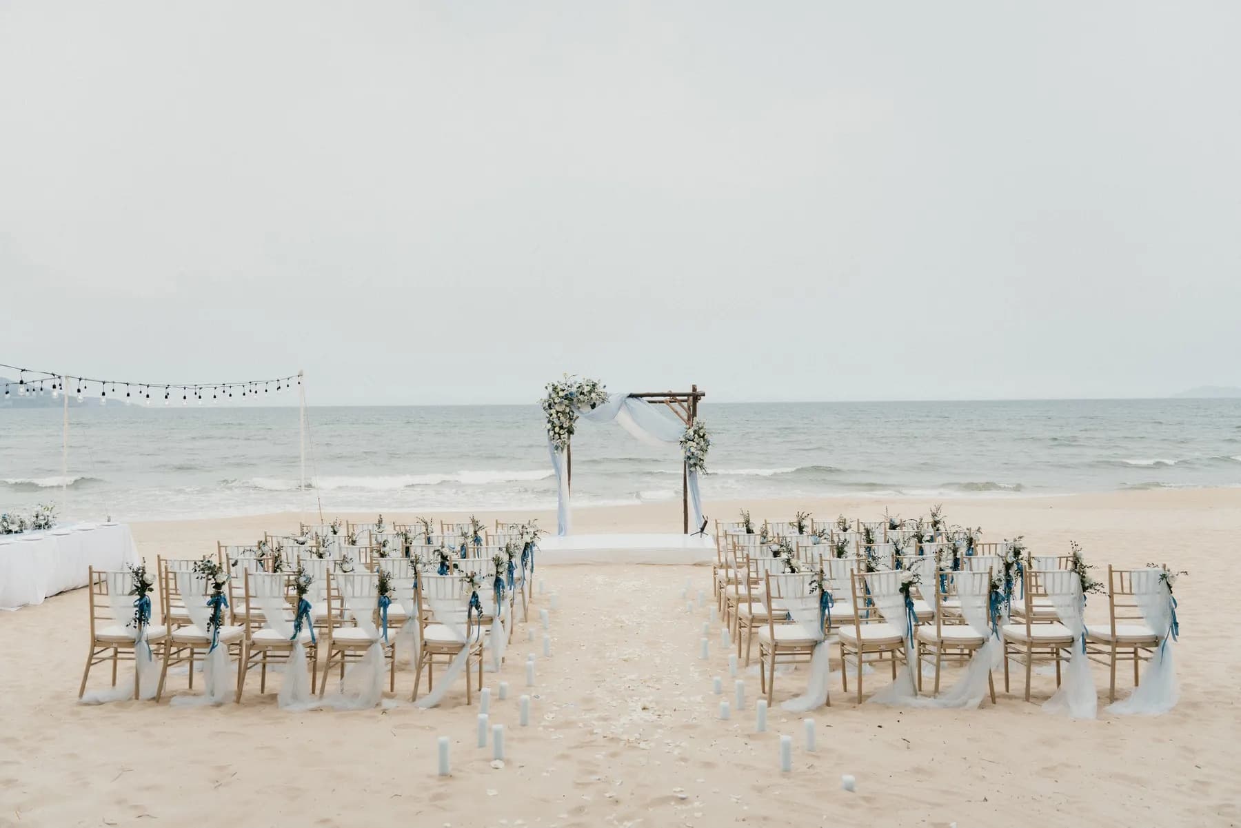Beach ceremony aisle with a floral arch facing the sea