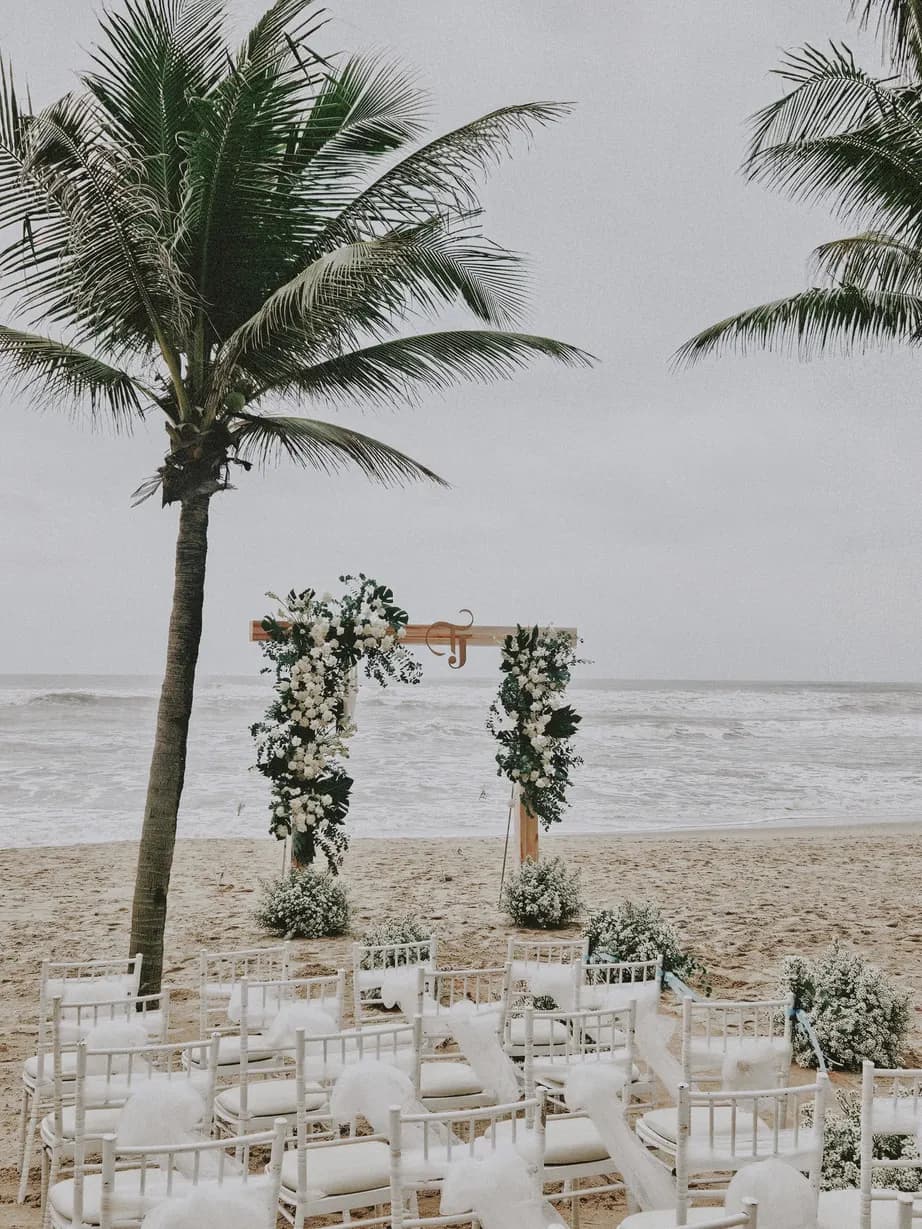 Ceremony arch and white chairs under a palm tree
